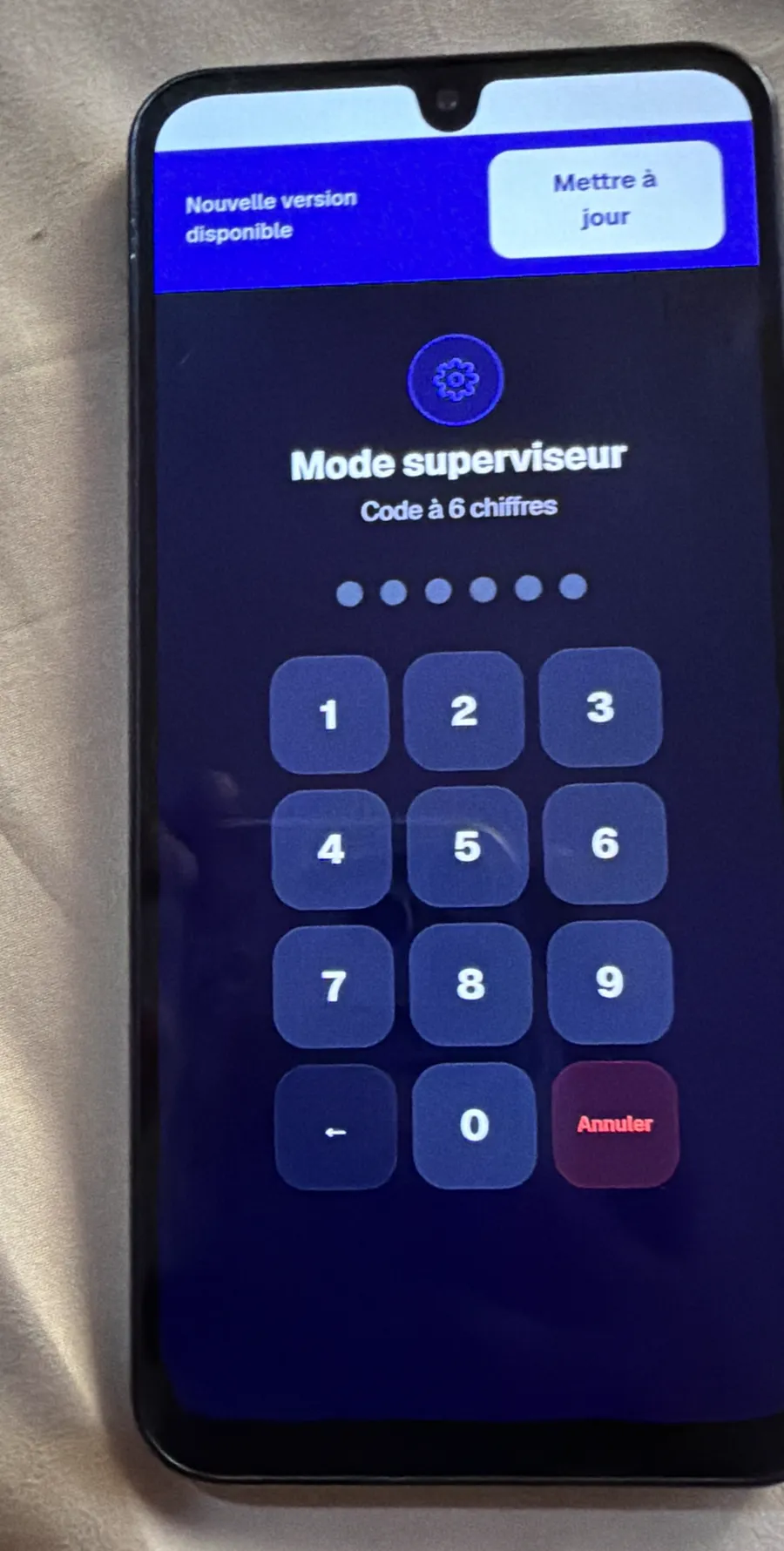 Un téléphone Android ordinaire posé sur un lit, avec la borne PRÉSENT à l’écran